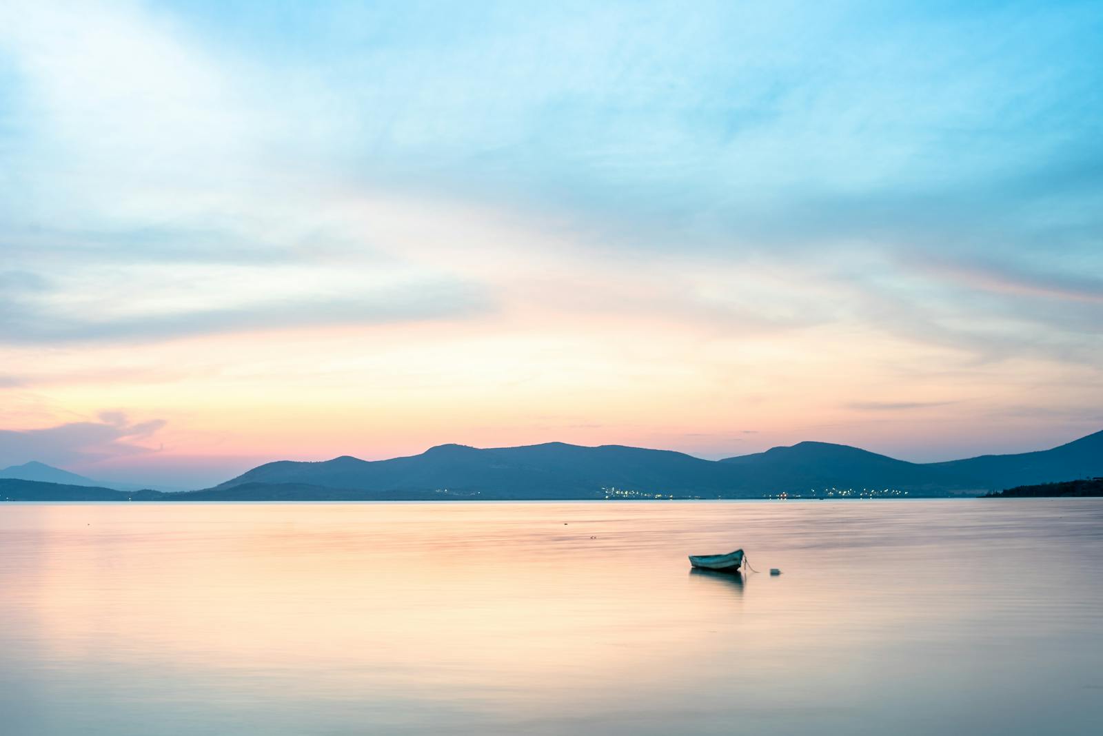 A small boat on a calm sea under a dramatic sky